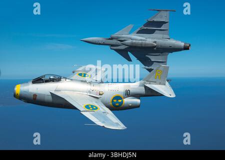 Ein Saab J29F Tunnan SE-DXB und Saab JAS-39C Gripen 39-225 führen während einer Fotosortie der schwedischen Luftwaffe einen synchronisierten Bankwechsel in Nahform durch. Stockfoto