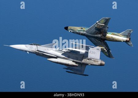 Dieses Luftbild zeigt zwei schwedische Luftwaffenflugzeuge: Die Saab JAS-39C Gripen (Reg. 39220, Militärcode 220) und die Saab-32 Lansen (Reg. 32542, Militärcode 4-23). Die Gripen ist ein Mehrzweckflugzeug, während die Lansen ein ausgemustertes Kampfflugzeug ist. Stockfoto