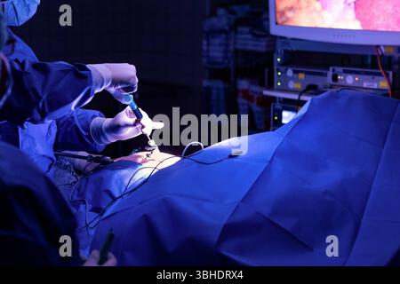 LK Osnabrück, Deutschland 30. Januar 2023: Im Bild: Ein kritischer Moment während einer Gallenblasenoperation in einem hochmodernen Operationssaal eines Krankenhauses. Ein medizinisches Fachpersonal, Arzt, gekleidet in steriler OP-Kleidung und mit chirurgischen Handschuhen, ist dabei, Gallenflüssigkeit mit Hilfe einer Spritze und spezieller Instrumente abziehen. Diese Instrumente werden durch kleine Zugänge, typisch für einen minimalinvasiven Eingriff z.B. Laparoskopie, in die Bauchdecke eingeführt. Die Präzision dieses Vorgangs ist entscheidend für den Erfolg der Operation und die Patientens Stockfoto
