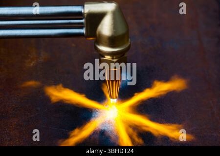 Gasschneiden von Metall. Gasschneider mit Kupferdüse mit einem auf das Metall gerichteten Brandstrahl. Erhitzen des Metalls mit einem Gasschneider. Stockfoto