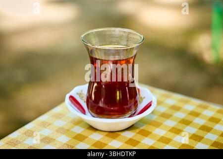 Eine Nahaufnahme aromatischen schwarzen Tees in einem klassischen Armudu-Glas auf einer hellen karierten Tischdecke. Stockfoto