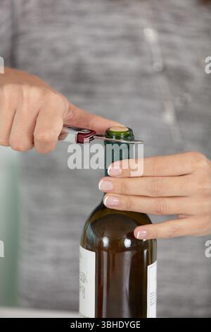 Hände öffnen eine Flasche Wein mit einem Messer Stockfoto