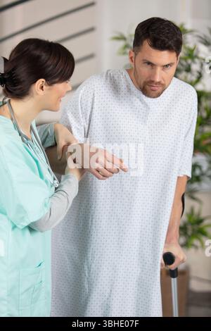 Medizinische Betreuung, die den Mann mit Krücken unterstützt Stockfoto