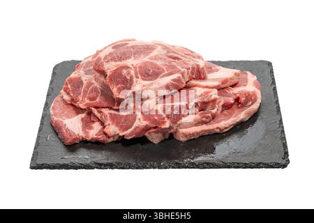 Gestapelte Schweinefleisch-Steaks auf einer Platte. Ein Stapel frischer Schweinefleisch-Steaks liegt auf einer schwarzen Platte. Die Stücke zeigen starke Fettmarmorierung und sind bereit für den gri Stockfoto