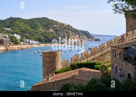 Ein malerischer Blick auf Tossa de Mar, mit den alten Burgmauern mit Blick auf eine ruhige Bucht voller Boote an einem klaren Tag. Stockfoto