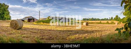 Großer Panoramablick auf eine ländliche Bauernlandschaft im Sommer in Buckinghamshire, Großbritannien, mit Heuballen, Scheunen und goldenen Feldern unter blauem Himmel Stockfoto