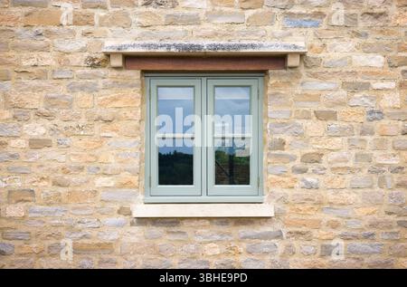 Grün lackiertes Holzfenster in einem Cotswold Steinhaus, Großbritannien Stockfoto