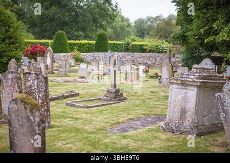 Alter englischer Friedhof mit verwitterten Grabsteinen bedeckt mit Moos und Flechten. Friedlicher ländlicher Friedhof, Großbritannien. Keine identifizierbaren Grabsteine. Stockfoto