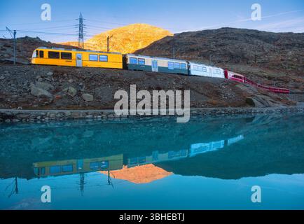 Bernina-Express-Zug und Bergsee mit bunten Reflexen Stockfoto
