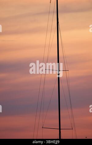Der Mast eines Segelbootes vor dem Hintergrund eines rosa Sonnenuntergangs Stockfoto