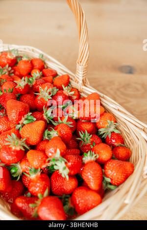 Frisch geerntete Erdbeeren, die in einem Korb gestapelt sind, zeigen ihre leuchtende rote Farbe und natürliche Textur. Saftig und reif sind diese Erdbeeren Stockfoto