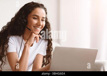 Nahaufnahme einer glücklichen jungen Frau mit Headset mit Laptop Stockfoto