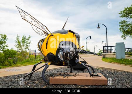 Eau Claire, WI, USA - 14. Mai 2025: Öffentliche Kunstskulptur einer Riesenbiene in der Nähe einer Brücke in Eau Claire Wisconsin Stockfoto