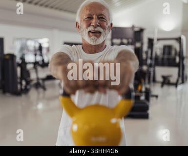 Selbstbewusster Senior, der Kettlebells für sein tägliches Fitnesstraining verwendet Stockfoto