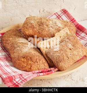 Dinkel-Ciabatta auf Holzoberfläche mit Oliven und Olivenöl im Hintergrund – ein rustikales Brot im mediterranen Stil, perfekt für Aperitif. Stockfoto