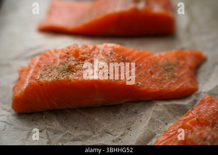 Frisches rohes Lachsfilet mit Kräutern auf Pergamentpapier Stockfoto
