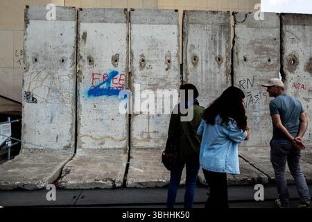 Paris, Frankreich. Juni 2025. Touristen spazieren vorbei an einer Ausstellung eines Bruchstücks der Berliner Mauer auf dem Trocadero-Platz. Der exponierte Abschnitt war mit Graffiti bedeckt, von denen einige explizite politische Botschaften enthielten: Anti-Polizei-Parolen wie ACAB, die Inschrift RN = NAZI und eine Botschaft der Unterstützung für die palästinensische Sache, DEN FREIEN GAZA. Letzteres wurde teilweise mit blauer Sprühfarbe gelöscht, wodurch die Botschaft der Solidarität weniger lesbar wurde. Juni 2024. Paare, Frankreich. - 08/06/2025 - Frankreich/Paris - Michael Bunel/Le Pictorium Credit: LE PICTORIUM/Alamy Live News Stockfoto
