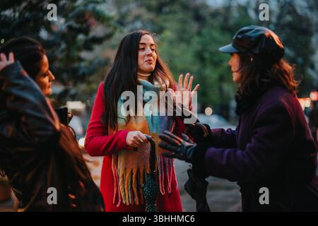 Drei Frauen, die während eines kalten Tages im Freien eine lebhafte Diskussion führen Stockfoto