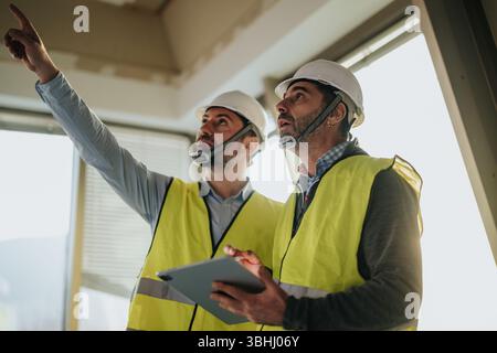 Zwei Bauexperten, die eine Baustelle mit Sicherheitsausrüstung inspizieren Stockfoto