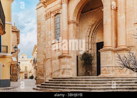 Ein eleganter Seiteneingang der Kathedrale Ciutadella de Menorca mit großen Säulen, einem bogenförmigen Eingang und komplizierten Steindetails. Die Mischung Stockfoto