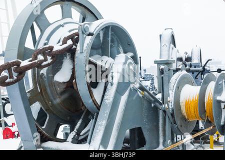 Das Anlegedeck eines Frachtschiffes mit Ankerwinden, einer Ankerkette an Winden, Pollern und Haws mit Anlegeseilen, gefroren und mit Schnee bedeckt. Sn Stockfoto