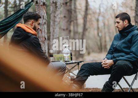 Zwei Freunde genießen ein zwangloses Winterpicknick in einer Waldlandschaft Stockfoto