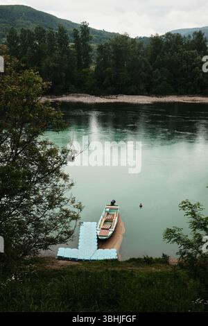 Ein kleines Holzboot vor Anker an einem schwimmenden Dock auf dem ruhigen Wasser des Drina-Flusses im serbischen Land im Frühling. Stockfoto