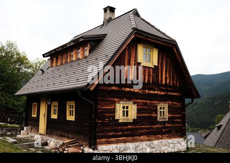 Traditionelles Blockhaus im Dorf Drvengrad, Serbien, mit gelben Holzfenstern und einem Steinfundament. Stockfoto