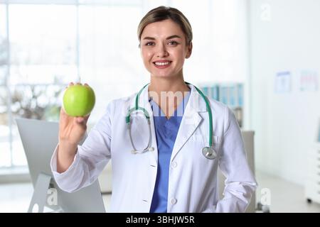 Ernährungsberater mit grünem Apfel und Stethoskop in der Klinik Stockfoto