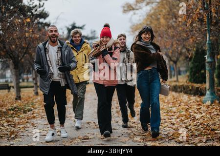 Gruppe von Freunden, die einen fröhlichen Herbstspaziergang im Park an einem bewölkten Tag genießen Stockfoto