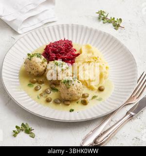 Deutsche Fleischbällchen in cremiger Kapernsauce. Traditionelle deutsche Fleischbällchen, bekannt als Königsberger Klopse, serviert in einer cremigen weißen Sauce mit Kapern. Stockfoto