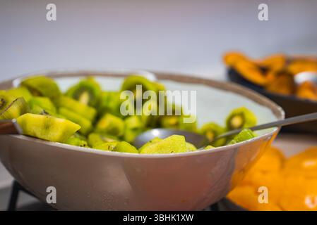 Nahaufnahme von frisch geschnittenen Kiwi-Scheiben in einer Schüssel mit Servierlöffel Stockfoto