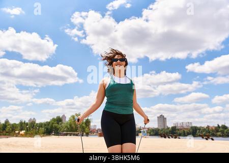 Eine junge Frau genießt ein Training, indem sie in einem sonnigen Outdoor-Park mit Seil springt und Selbstvertrauen ausstrahlt. Stockfoto