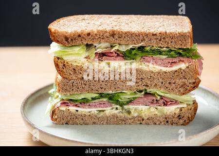 UK. Ein großzügiges Pastrami-Sandwich im New Yorker Stil, serviert auf braunem Roggenbrot mit Salat und Mayo-Dressing. Stockfoto