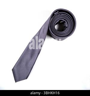 Eine schwarze Krawatte, die auf weißem Hintergrund gerollt ist Stockfoto