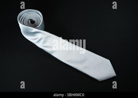Eine Krawatte rollte auf schwarzem Hintergrund Nahaufnahme Stockfoto
