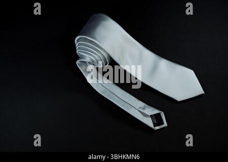 Eine Krawatte rollte auf schwarzem Hintergrund Nahaufnahme Stockfoto