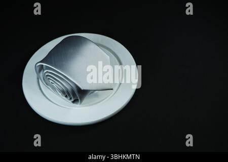 Eine Krawatte rollte auf schwarzem Hintergrund Nahaufnahme Stockfoto