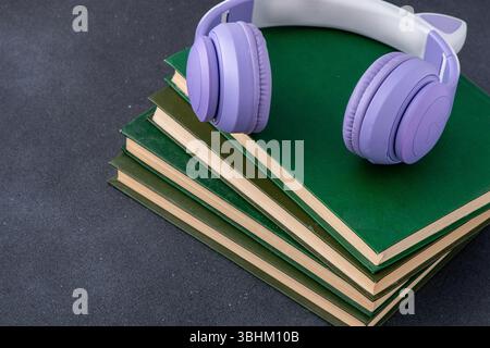 Kabellose Kopfhörer mit Büchern auf schwarzem Hintergrund. Studienausbildung. Buchhandlung. Hörbuch Stockfoto