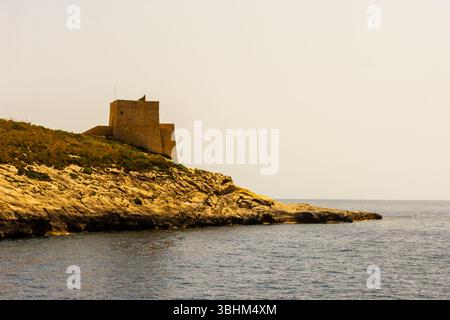 Historischer Steinturm mit Blick auf das Meer in einer sonnigen Küstenlandschaft Stockfoto
