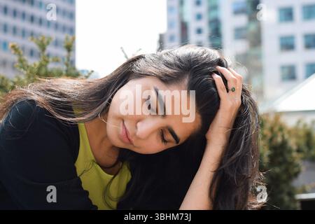Junge Frau, die auf der Stadtstraße sitzt und sich traurig verärgert fühlt, überfordert Stockfoto