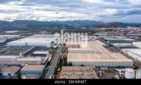 Puerto de Sagunto - Valencianische Gemeinschaft - Spanien- 01-01-2025: Aus der Vogelperspektive auf das Industriegebiet Sagunts mit großen Lagerhäusern, Fabriken, Lkw, Umgebung Stockfoto