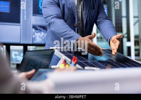 Investoren untersuchen die Oberfläche von Solarpaneelen und besprechen die Effizienz der Konstruktion mit den Managern der Fabrik. Geschäftsleute treffen sich mit dem Manager, um über technische Verbesserungen an Solarzellen zu sprechen Stockfoto