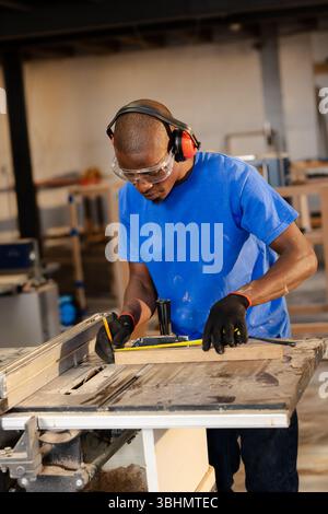 Holzdiele, die auf der Tischsäge aufliegt, wird in einer viel befahrenen Tischlerei präzise vermessen Stockfoto