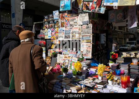 Shopper an einem Zeitungs- und Buchstand im Einkaufsviertel Plaka, Zentral-Athen, Griechenland. Stockfoto