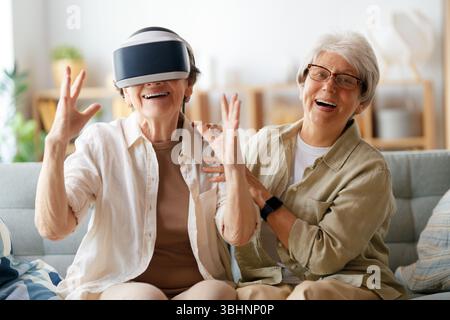 Zwei ältere Frauen spielen Konsolenspiele mit vr-Brille zu Hause. Stockfoto