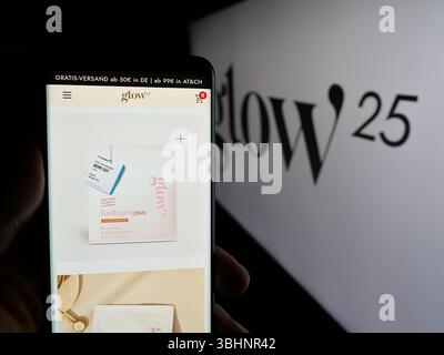 Stuttgart, Deutschland - 20.03.2025: Handybesitzer mit Webseite des deutschen Kollagenunternehmens Glow25 (Primal) auf dem Bildschirm vor dem Logo Stockfoto