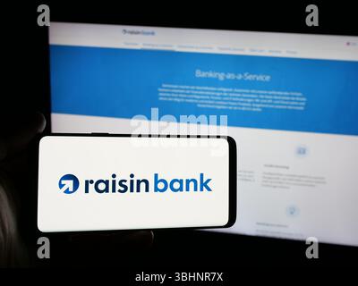 Stuttgart, Deutschland - 20.03.2025: Person, die ein Smartphone mit dem Logo der deutschen Finanzgesellschaft Raisin Bank AG auf dem Bildschirm vor der Website hält. Stockfoto