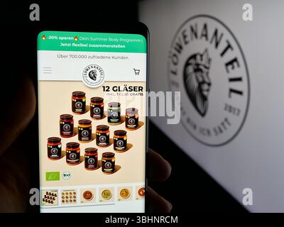 Stuttgart, Deutschland - 20.03.2025: Handybesitzer mit Webseite des deutschen Bio-Lebensmittelunternehmens Löwenanteil GmbH auf dem Bildschirm vor dem Logo. Stockfoto