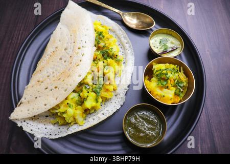Crispy Masala Dosa ist ein beliebtes südindisches Gericht, das mit Tomatenchutney, Kokos-Chutney, scharfer Kartoffelmasala oder Aloo KI Sabzi und Sambar serviert wird. Stockfoto